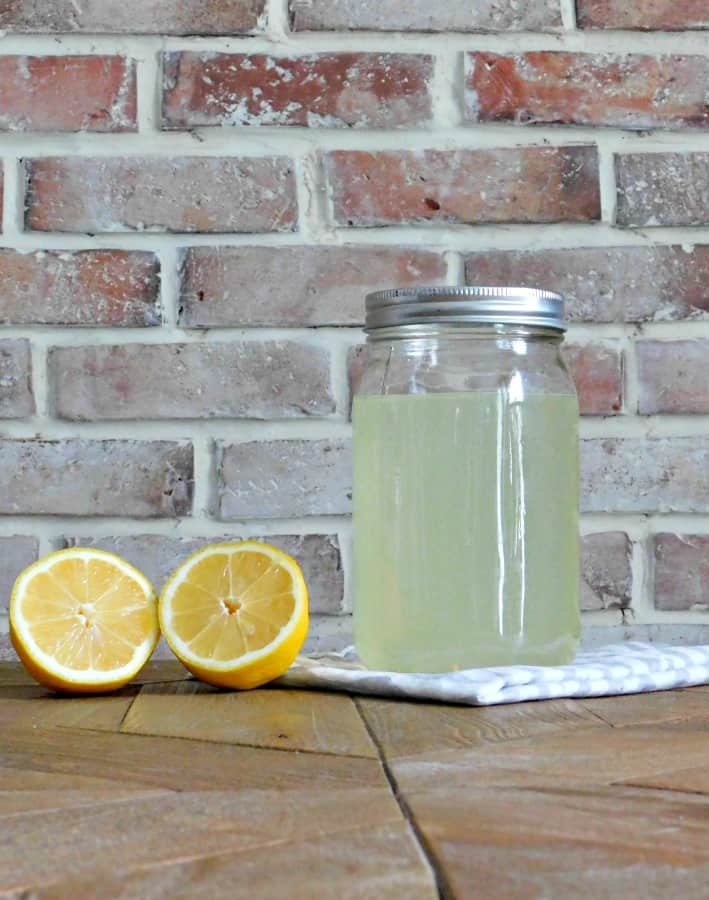 homemade bleach alternative in mason jar with sliced lemons beside it