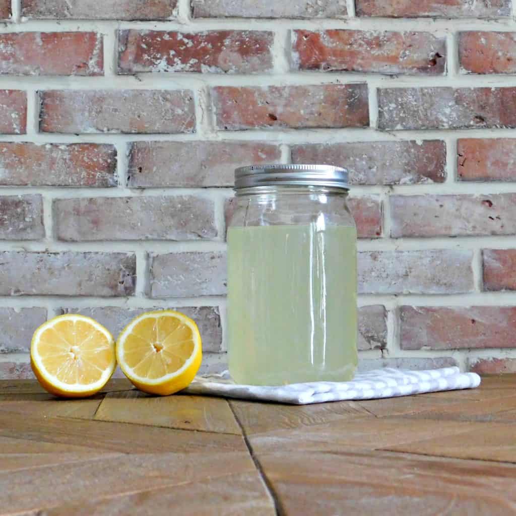 homemade bleach in mason jar beside cut lemon on wood table
