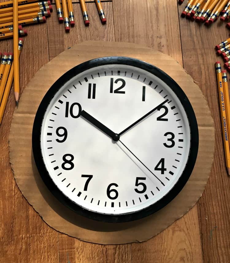 school clock on circle of cardboard with pencils around it