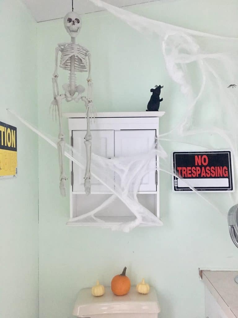 a skeleton hangs from the ceiling and a no trespassing sign is posted on the wall. 