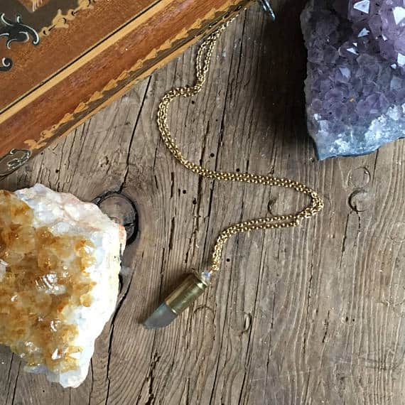 Crystal Bullet Necklace on wood table with purple and yellow crystal clusters