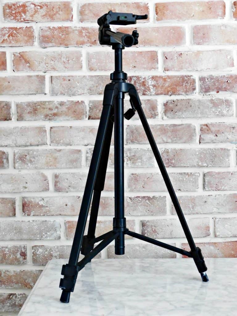 camera tripod in front of brick wall