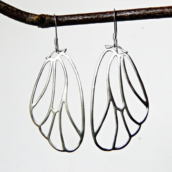 silver butterfly wing earrings hanging from branch
