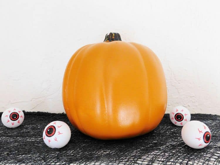 Fake pumpkin on black fabric with little eyeballs on display