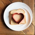 using the heart shaped cookie cutter to cut out a heart of the bread