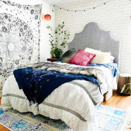 hygge bedroom with beautiful wall hanging and bright colored pillows
