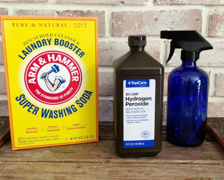 washing soda, hydrogen peroxide and a spray bottle on a wood table.