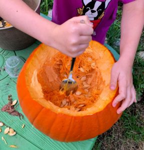 child scooping out a pumpkin