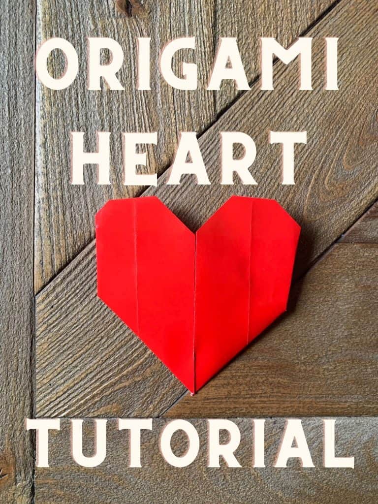 red origami heart on wood table with text over top. 