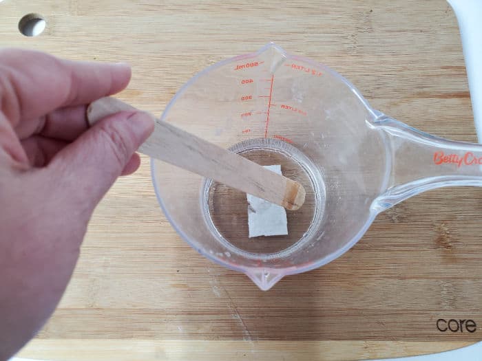 Mixing the ingredients in a measuring cup with a wooden stir stick. 