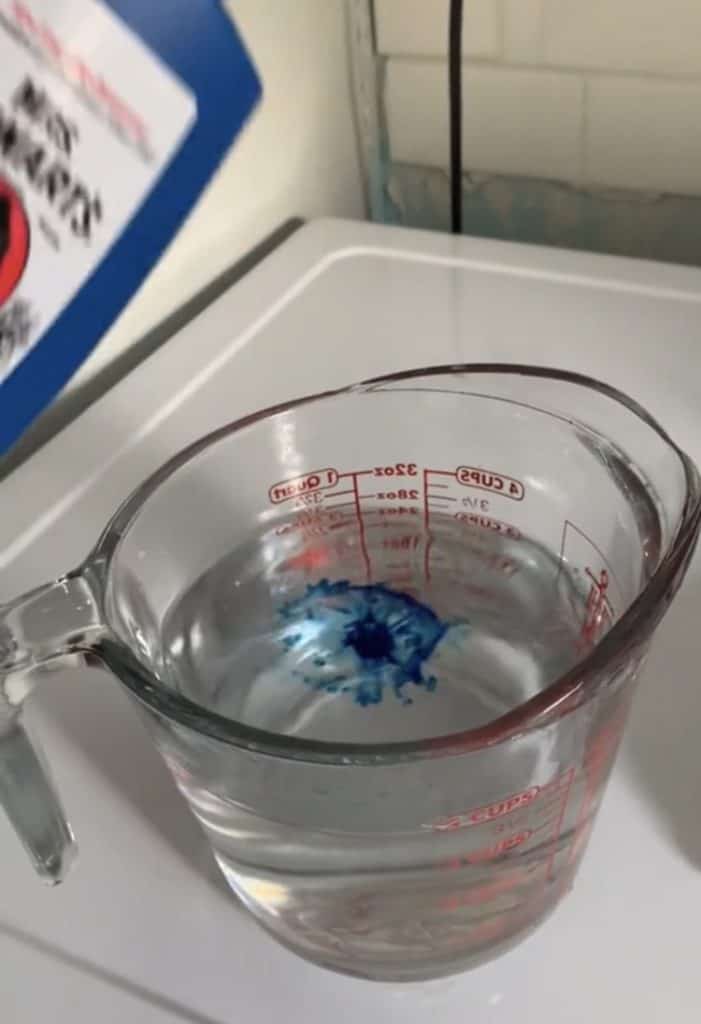 A few drops of the laundry bluing in a measuring cup full of water. 