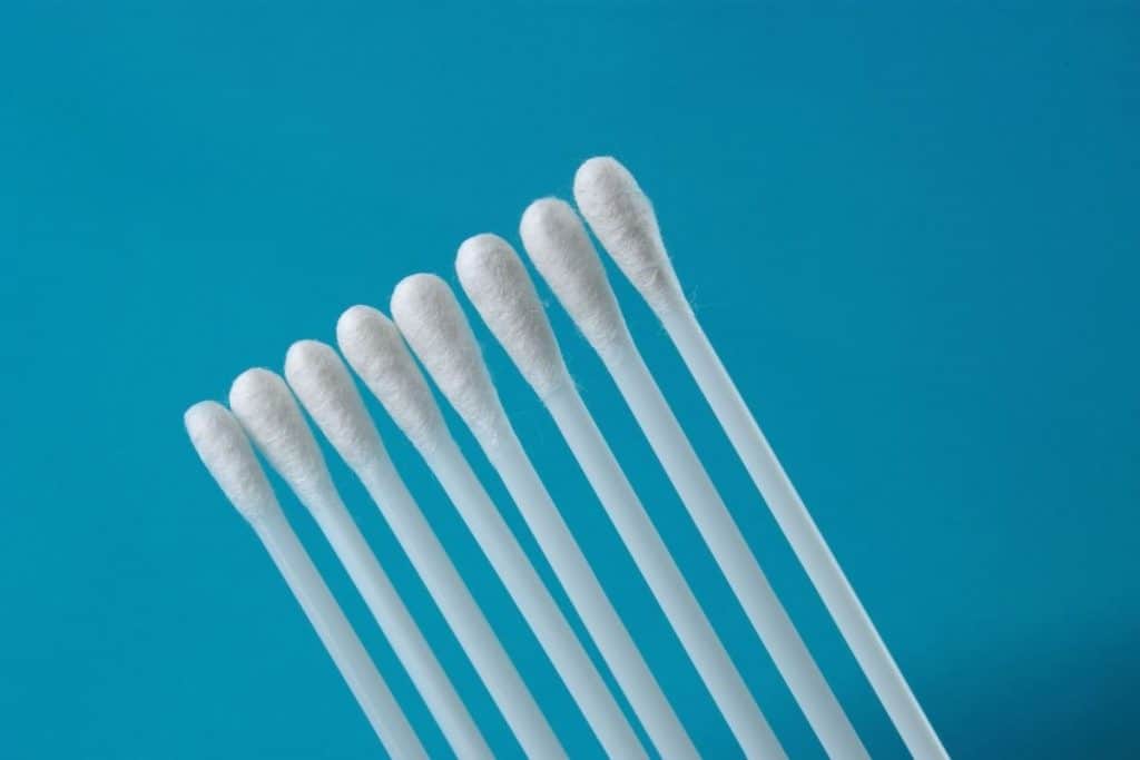 Close up of white q tips in front of a blue background. 