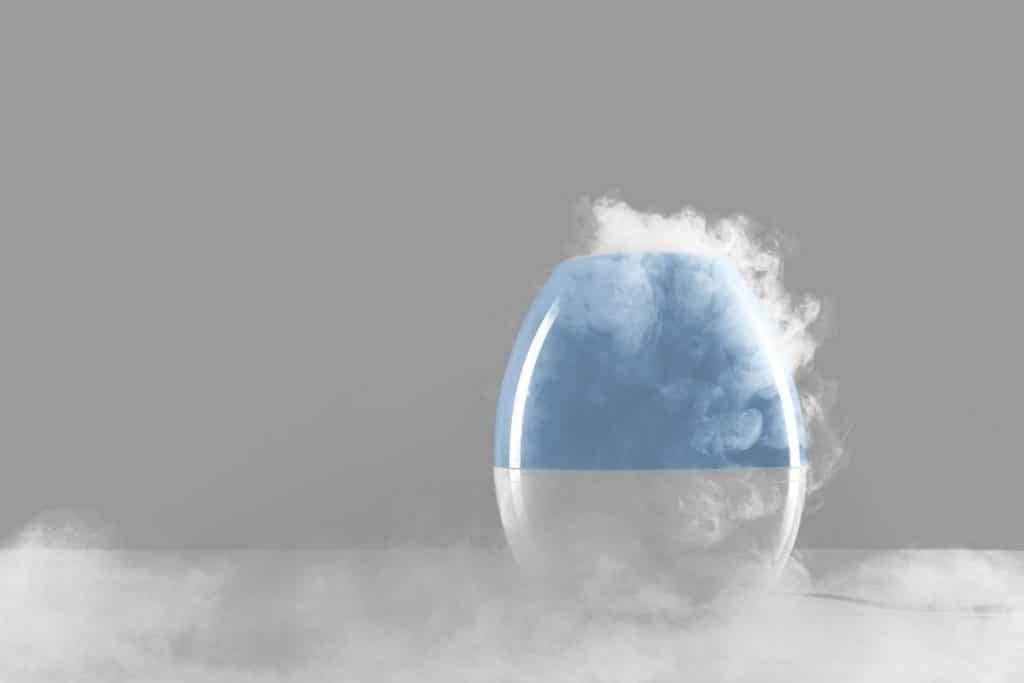 Blue and white humidifier with steam coming out of the top. 