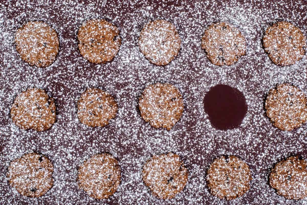 Cookies covered with powdered sugar on a baking sheet. 