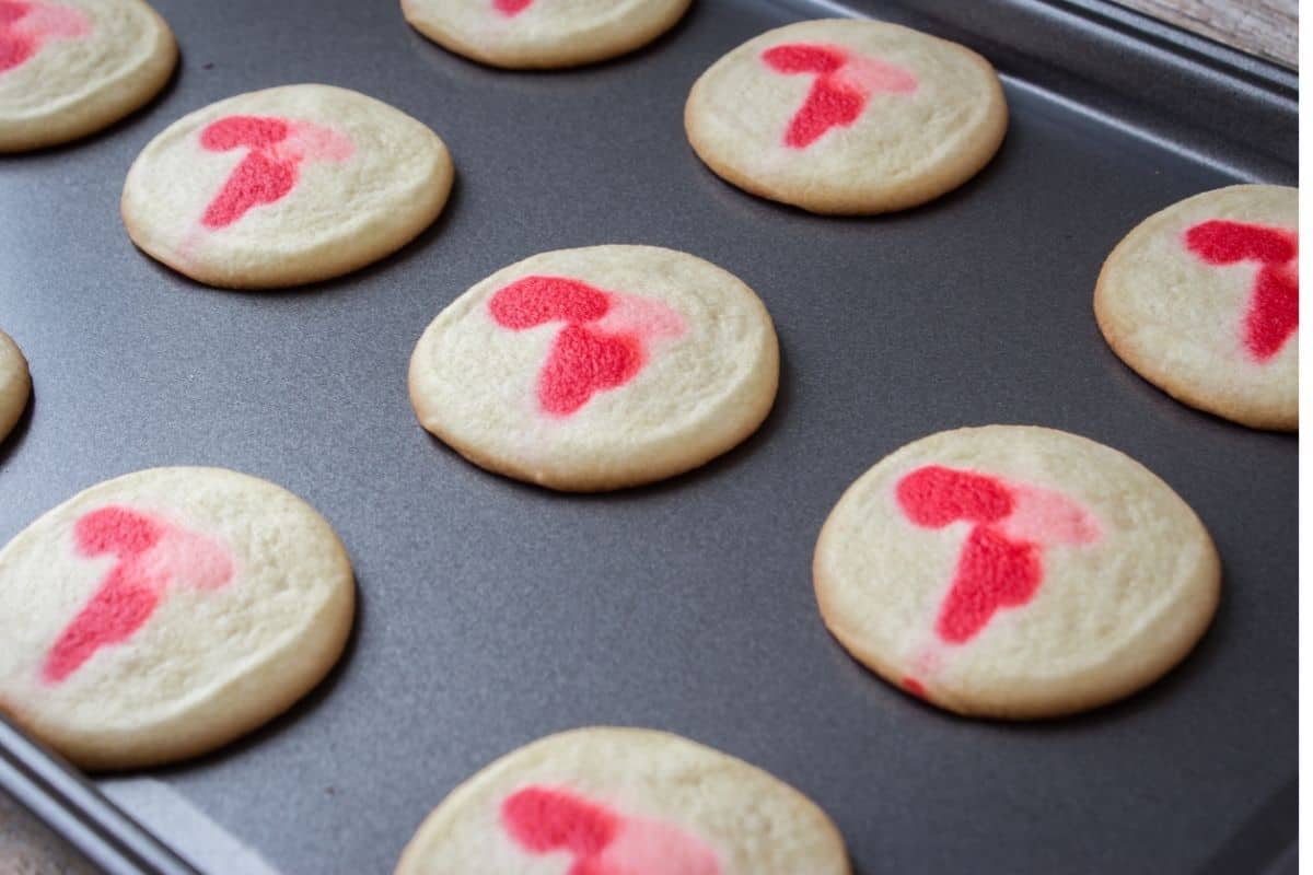 Red and white cookies on a baking sheet. 