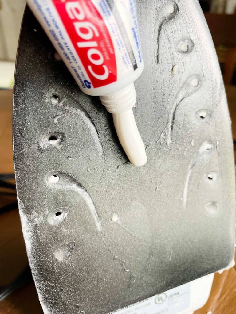 Toothpaste being applied to the plate of an iron to clean it. 