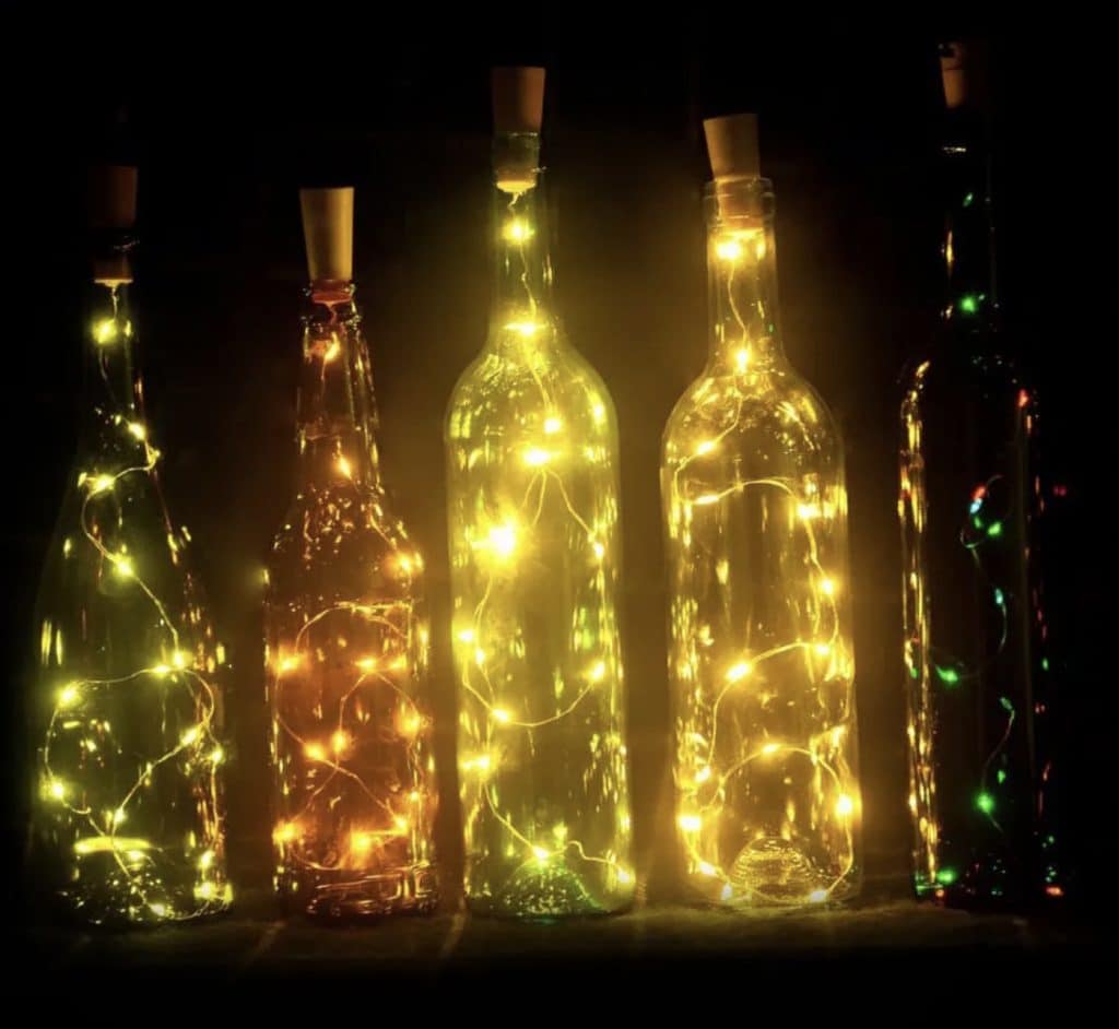 Row of bottles lit up with fairy lights. 