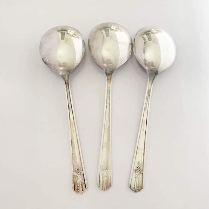 Clean set of silverware laid out on a white table that have had the tarnish removed with Coca Cola. 
