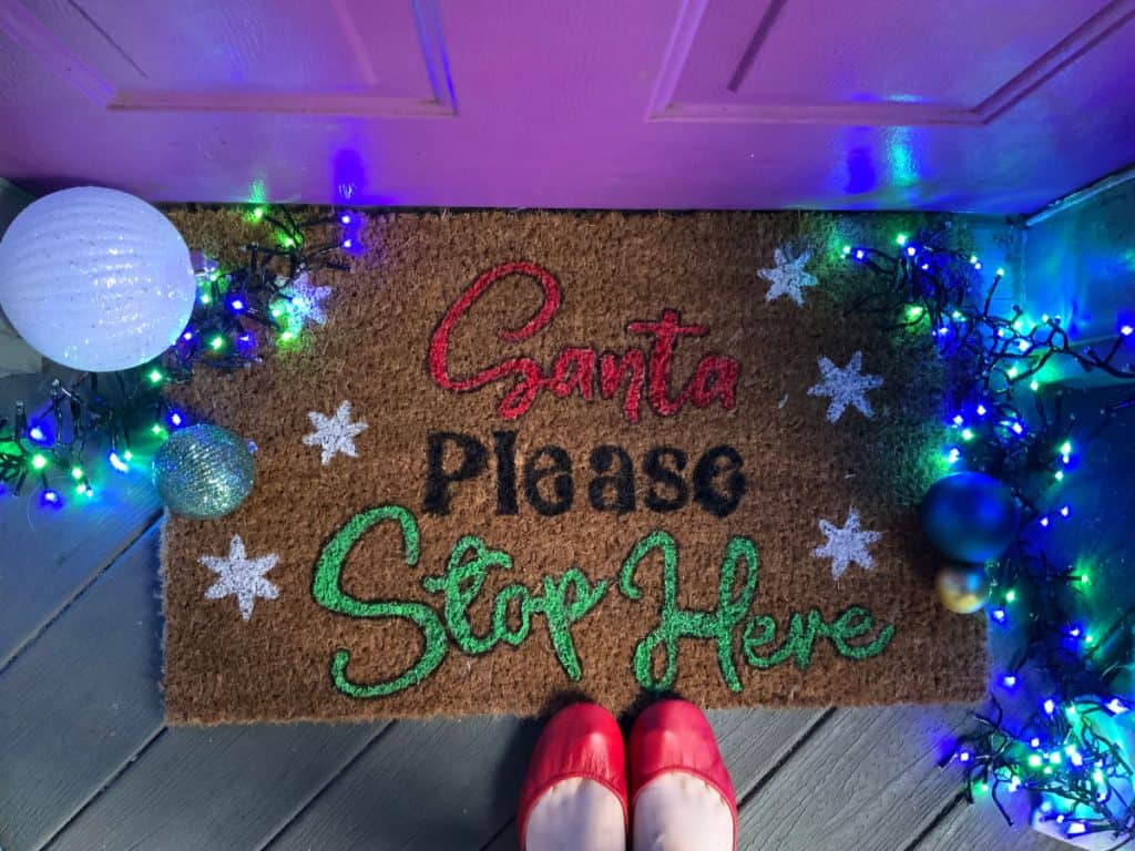 DIY Doormat with Christmas lights and red shoes placed on it.