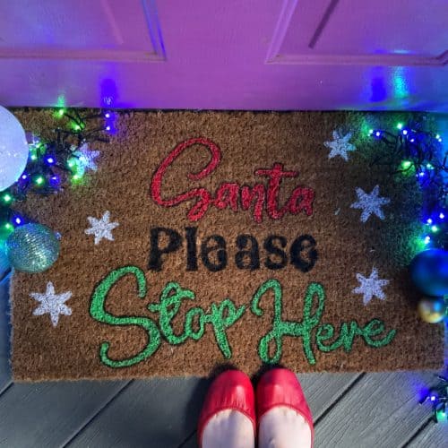 DIY Doormat with Christmas lights and red shoes placed on it.