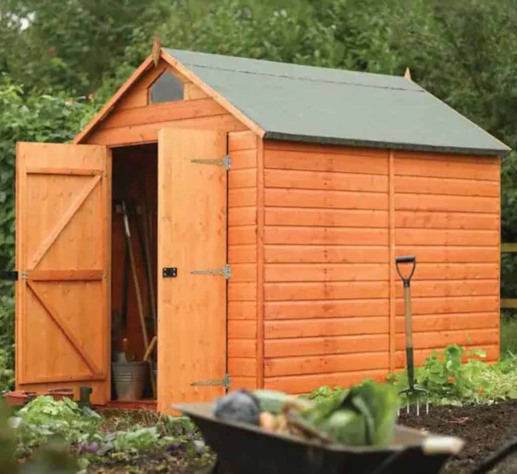 Wood shed in a garden with the door ajar. 