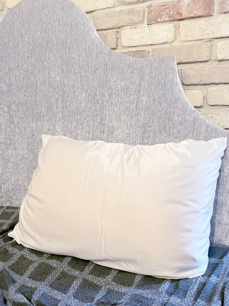 silk Pilllow case on a bed with a grey headboard and checkered sheets. 