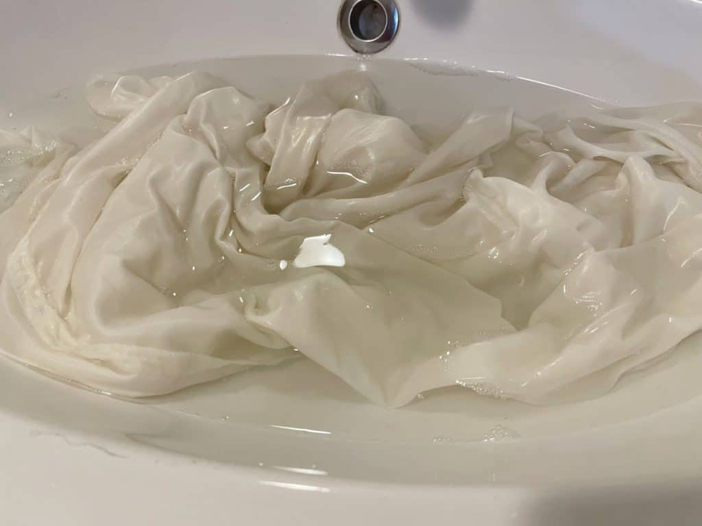 Silk pillow case being soaked in a sink with cool water. 