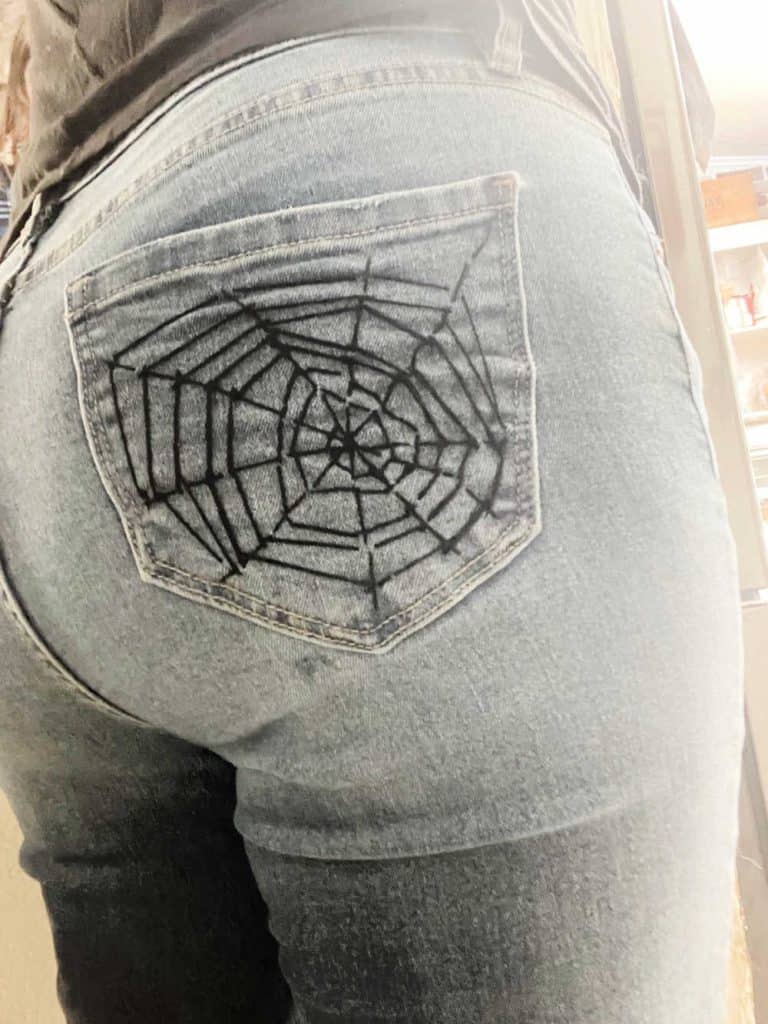 Spider web embroidery on the back pocket of a pair of jeans. 