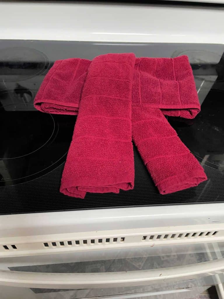 Red dish towels folded on top of an oven to make a bow. 