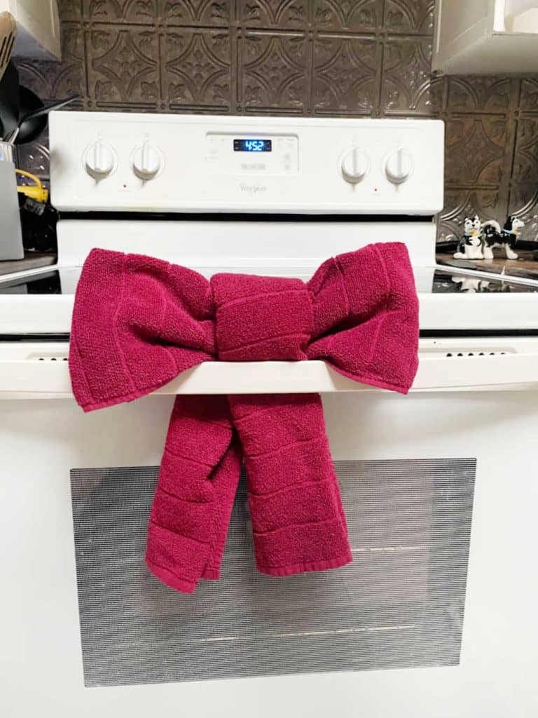 Red bow made from a towel hanging from an oven handle. 
